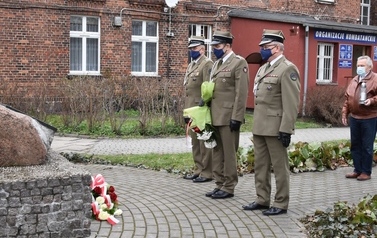 Na zdjęciu trzech delegat&oacute;w Stowarzyszenia Tczewskich Saper&oacute;w składają kwiaty pod tablicą z nazwiskami saper&oacute;w, kt&oacute;rzy zginęli podczas odminowywania teren&oacute;w kociewskich po zakończeniu II Wojny Światowej